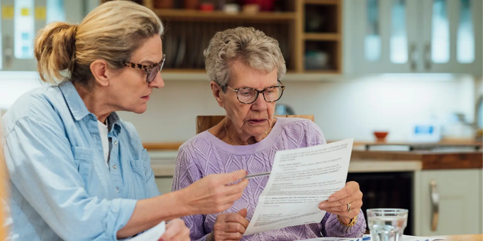 a middle aged woman is helping an older relative check paperwork and finances